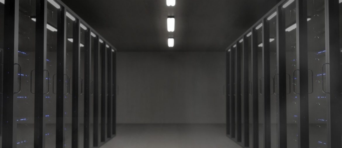 Modern data center with illuminated server racks in a dimly lit aisle, showcasing advanced technology and infrastructure.