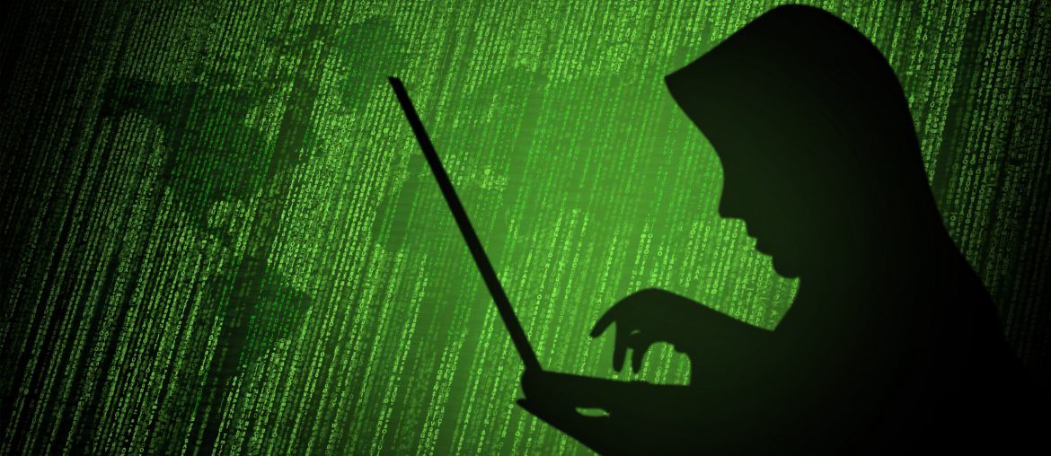 My Domain Name Was Hijacked, What Do I Do? Silhouette of a person in a hoodie typing on a laptop against a backdrop of green binary code and digital world map