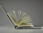 Open laptop with a book standing upright on the keyboard, pages fanned out, representing technology and education.