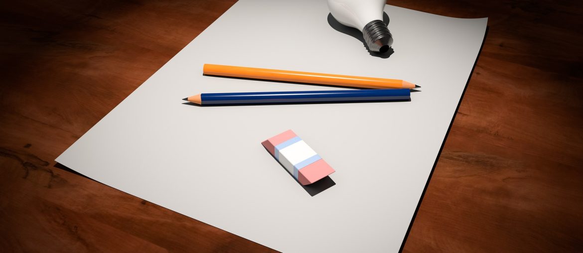 Pencils, eraser, and light bulb on a white sheet of paper placed on a wooden desk