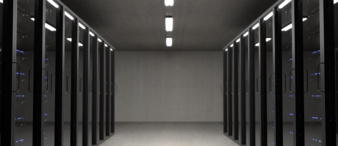Is Shared Hosting Still Good in 2023 Modern data center server room with rows of black server racks, illuminated by overhead fluorescent lighting.