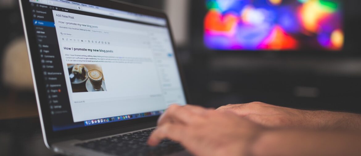 Person typing on a laptop, writing a blog post about promoting content, with a colorful screen in the background.