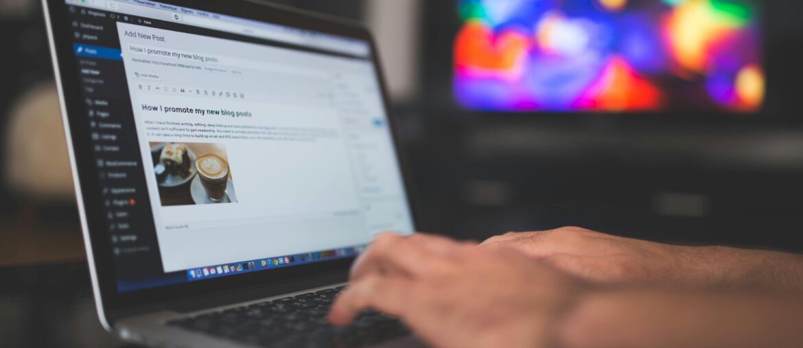 Blog vs. Vlog – Which One is Better? Person typing on a laptop with a blog editing interface open, blurred colorful screen in the background.